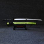 Professional photo of the #1 Neon Marble Samurai Katana with a unique phosphorus green marble scabbard and 104cm silver wooden blade, displayed on a wooden stand in a modern gaming setup with dynamic RGB lighting.